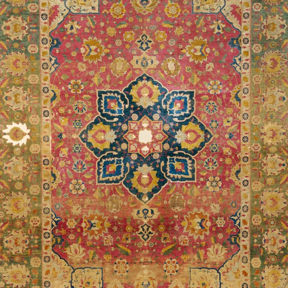 A sixteenth-century silk Kashan carpet with rose field, indigo medallion, gold details, and pale borders